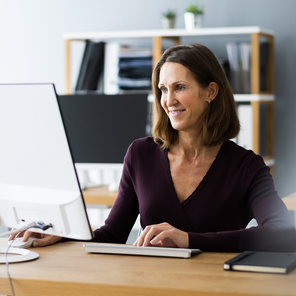 Professional sitting at desk looking at large monitor