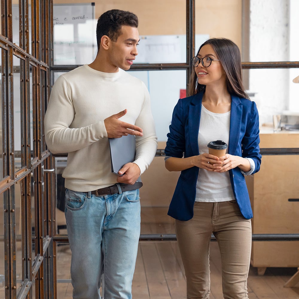 Two people walking down a hallway and conversing