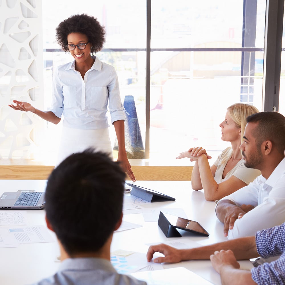 Person presenting to co-workers in a conference room setting