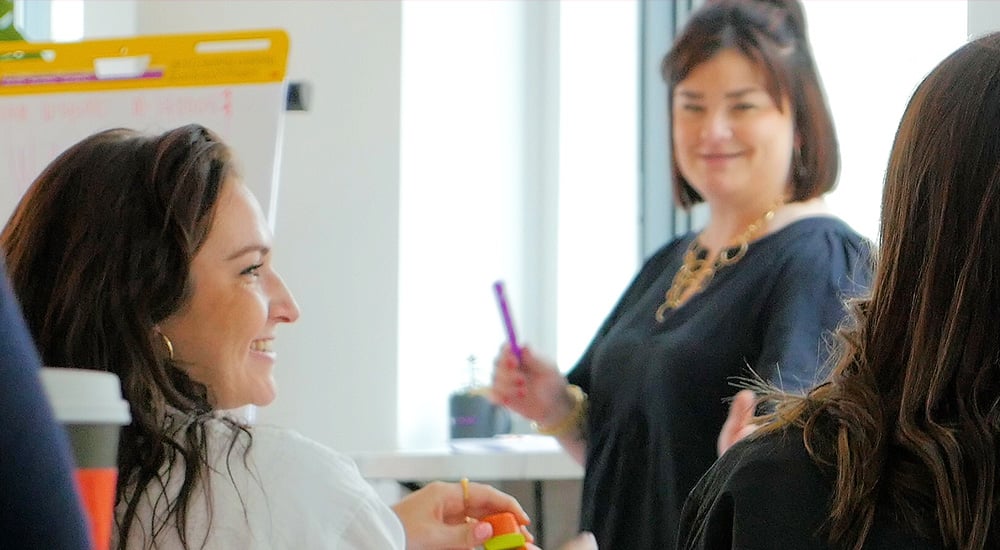 Three women working with flip charts, smiling