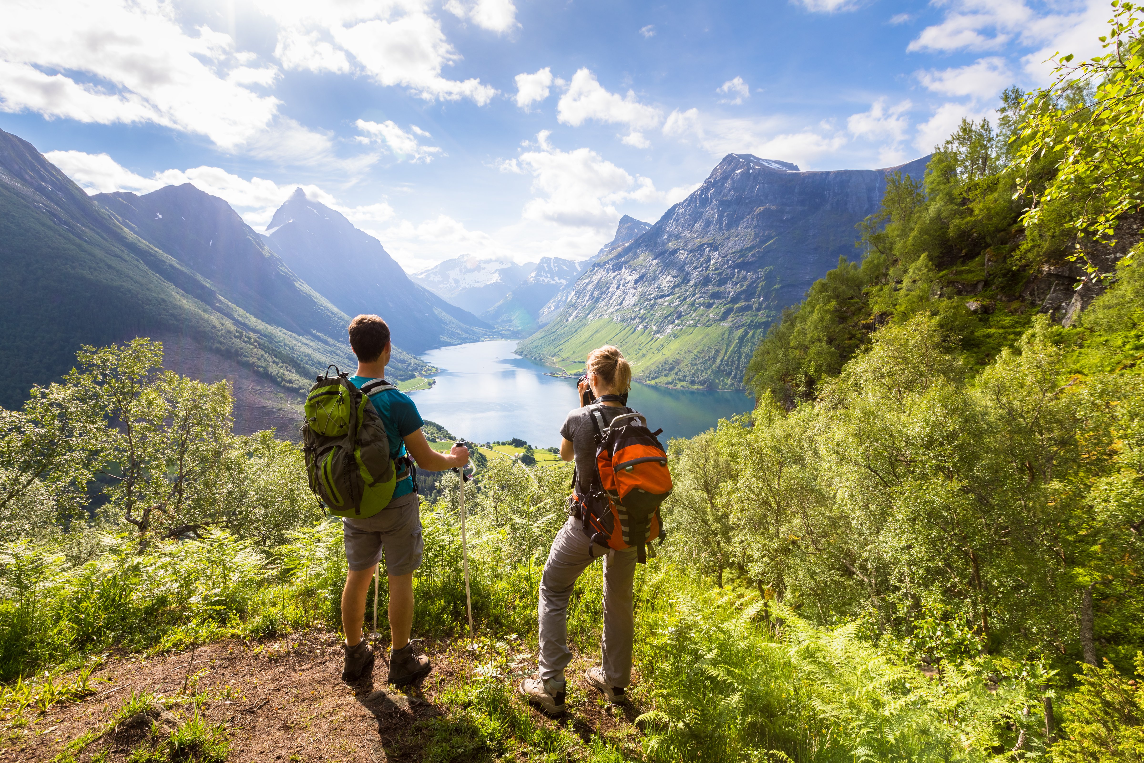 man and woman, hiking in the mountains, looking at a mountain lake in a valley in the distance