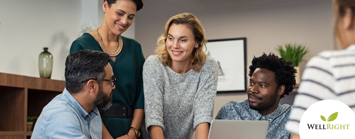 Two woman and one man face a bearded man as he demonstrates somethingshown on a laptop