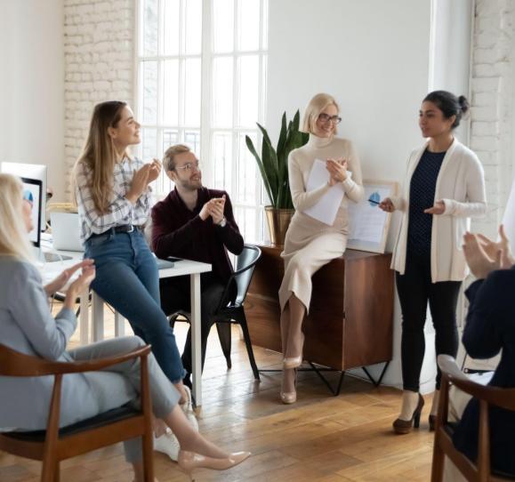 group of people clapping as they listen to a presentation in a casual sitting