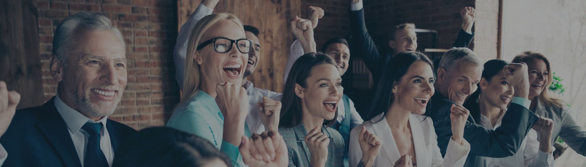 Group of business people sitting in a line, cheering with fists raised in the air