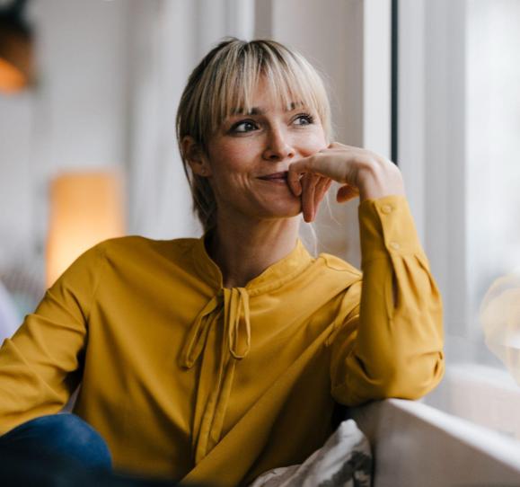 Blond hair woman in merigold blouse looking out window